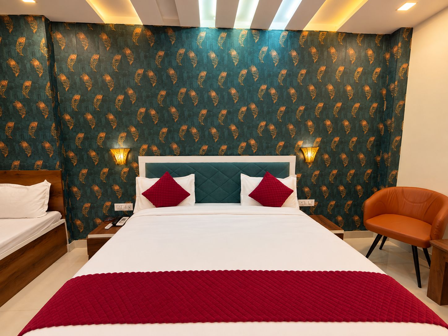 Una habitación de hotel con una cama grande, dos mesitas de noche, una silla y un papel tapiz estampado.