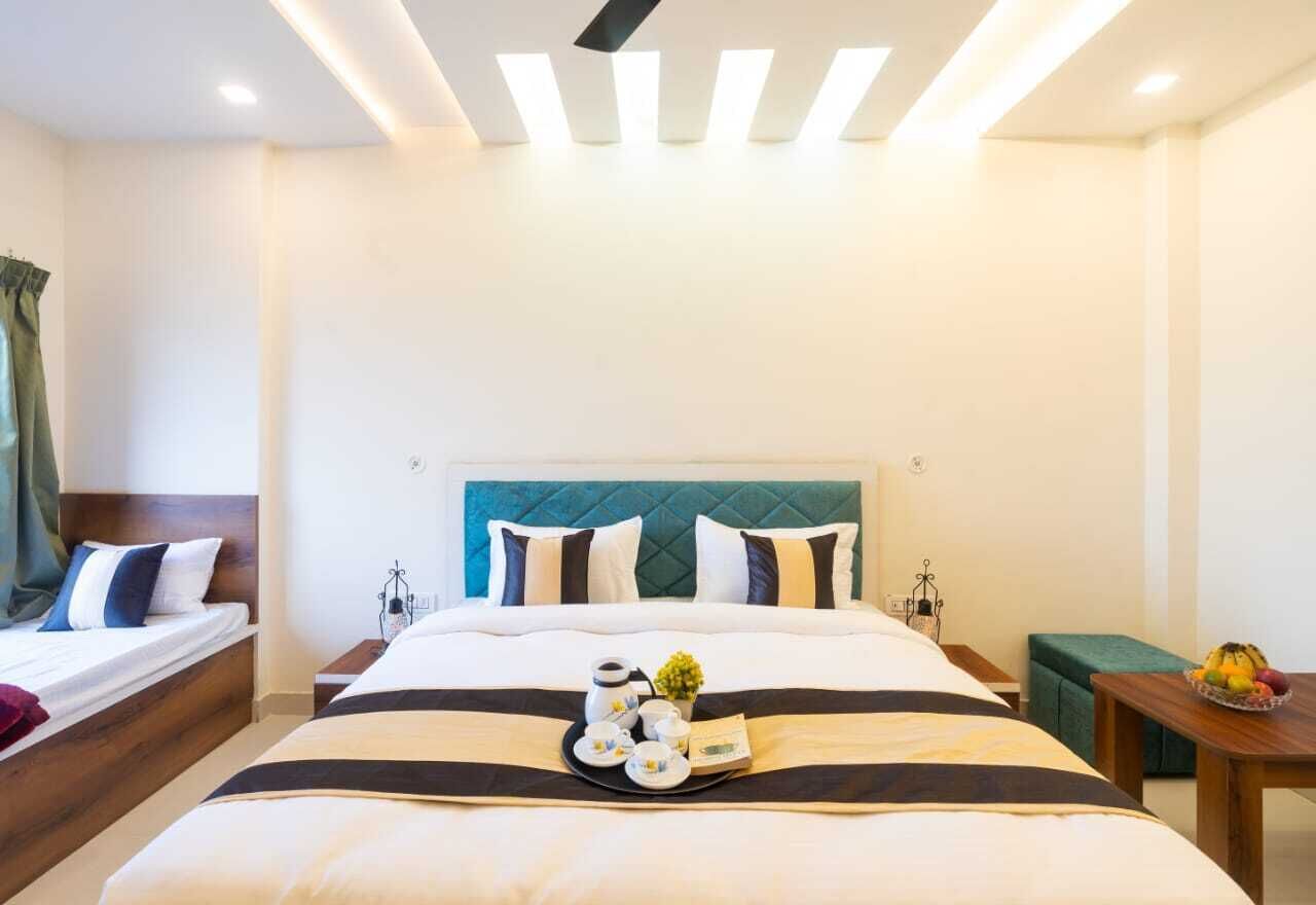 A hotel room with a large bed, a bedside table with a tray of breakfast items, and a small table with fruit.