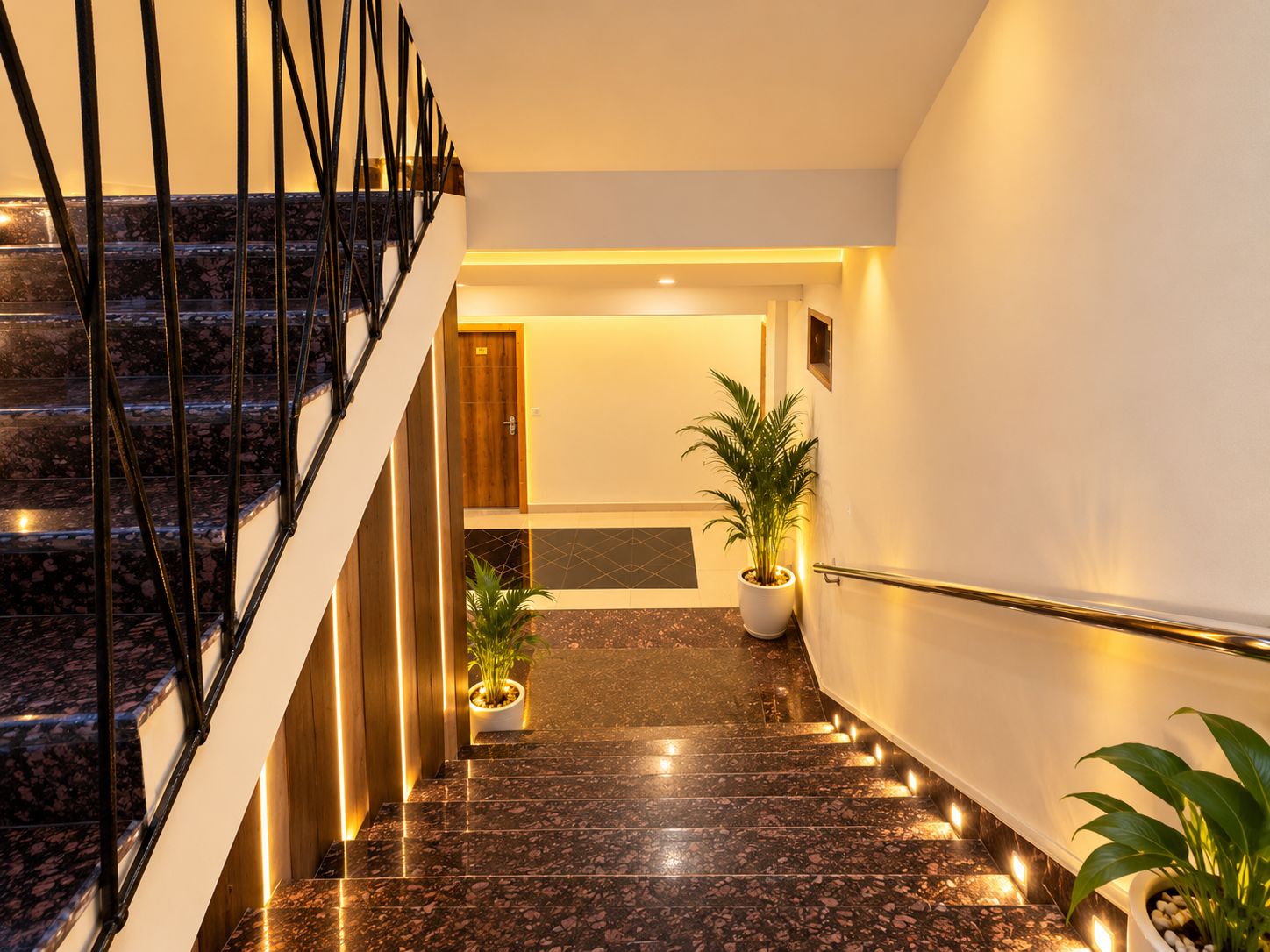 Ein modernes Hotel-Interieur mit einer Marmortreppe, einem Empfangsbereich und Zimmerpflanzen.