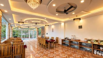 A spacious dining area with wooden furniture, a patterned floor, and ceiling fans.