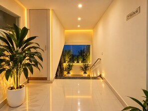 A well-lit hallway with a staircase leading to the 2nd floor, potted plants, and a clean, modern design.