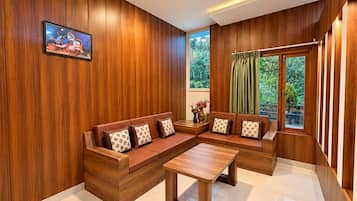 Una sala de estar moderna con paneles de madera, un sofá modular con cojines estampados, una mesa de centro y un ventanal con vistas a zonas verdes.
