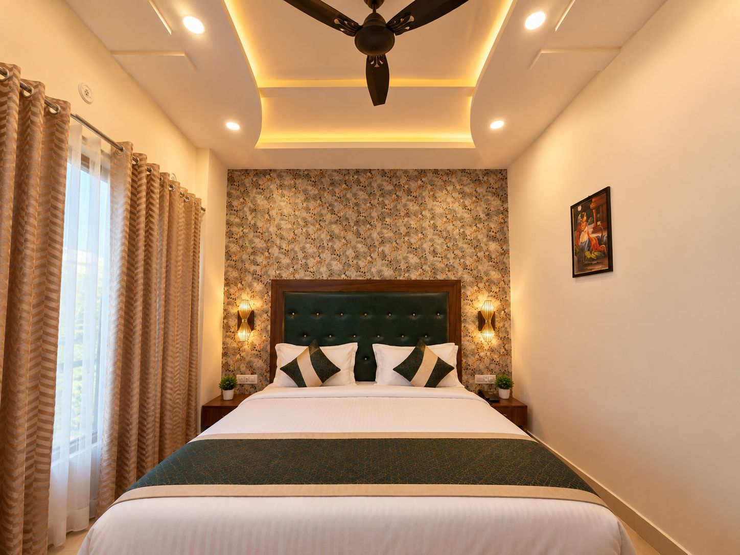 A hotel room with a large bed, a ceiling fan, wall-mounted sconces, and a floral wallpaper pattern.