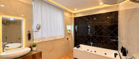 A modern bathroom with a large bathtub, a vanity with a mirror, and a shower area.