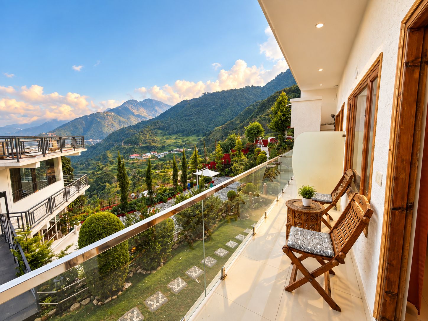 A balcony with a view of a mountainous landscape, a wooden chair, and a small table with a plant.