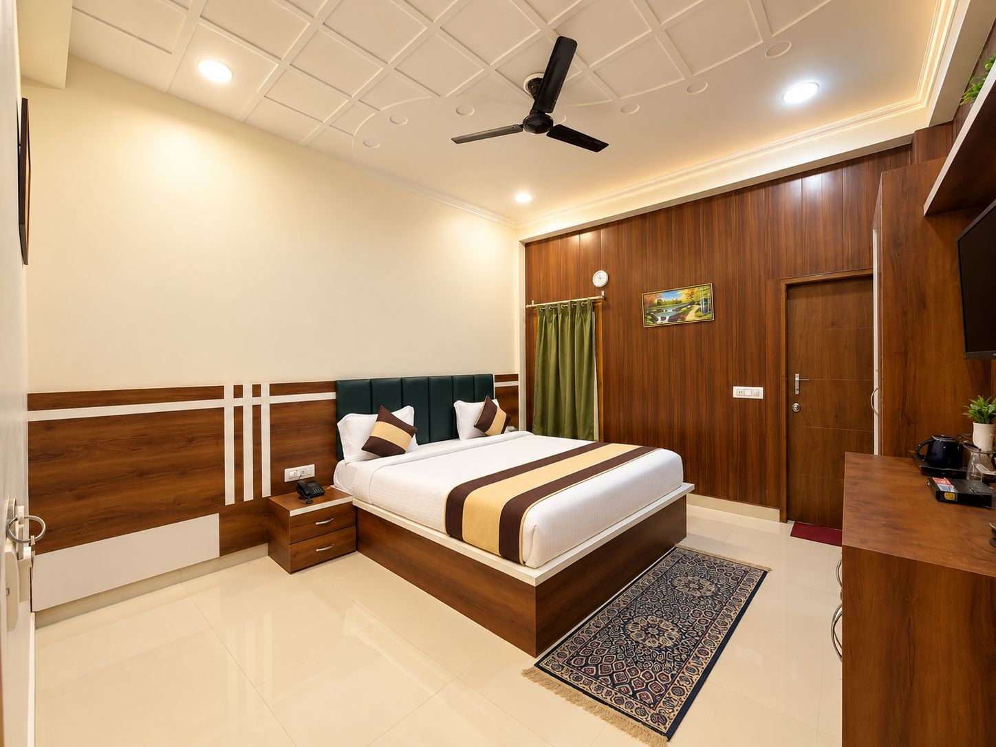 A hotel room with a large bed, a desk, a ceiling fan, and a wooden wardrobe.
