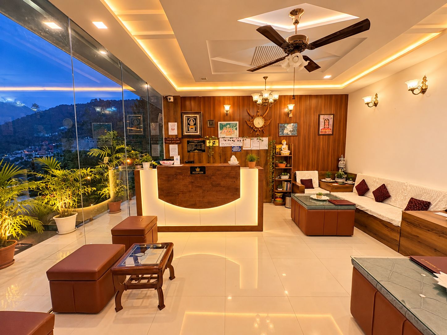 Zona de recepción de un hotel con mostrador, asientos, ventilador de techo y vista panorámica de la ciudad.