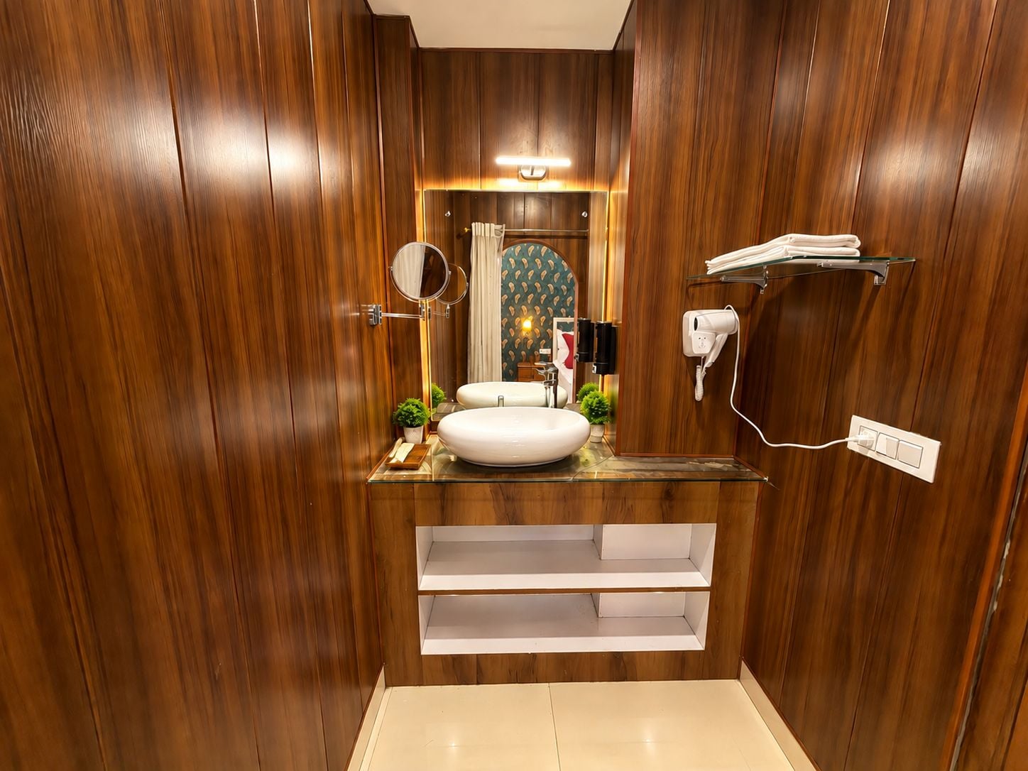 A bathroom with wooden paneling, a round mirror, a white sink, a towel rack, and a hairdryer.