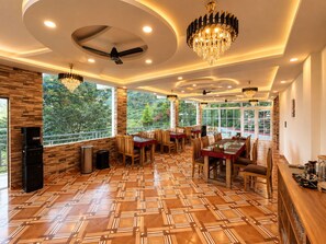 A restaurant with a modern interior, large windows, and a patterned floor. - Hotel Luxmi Vilas Inn (Dhanaulti)