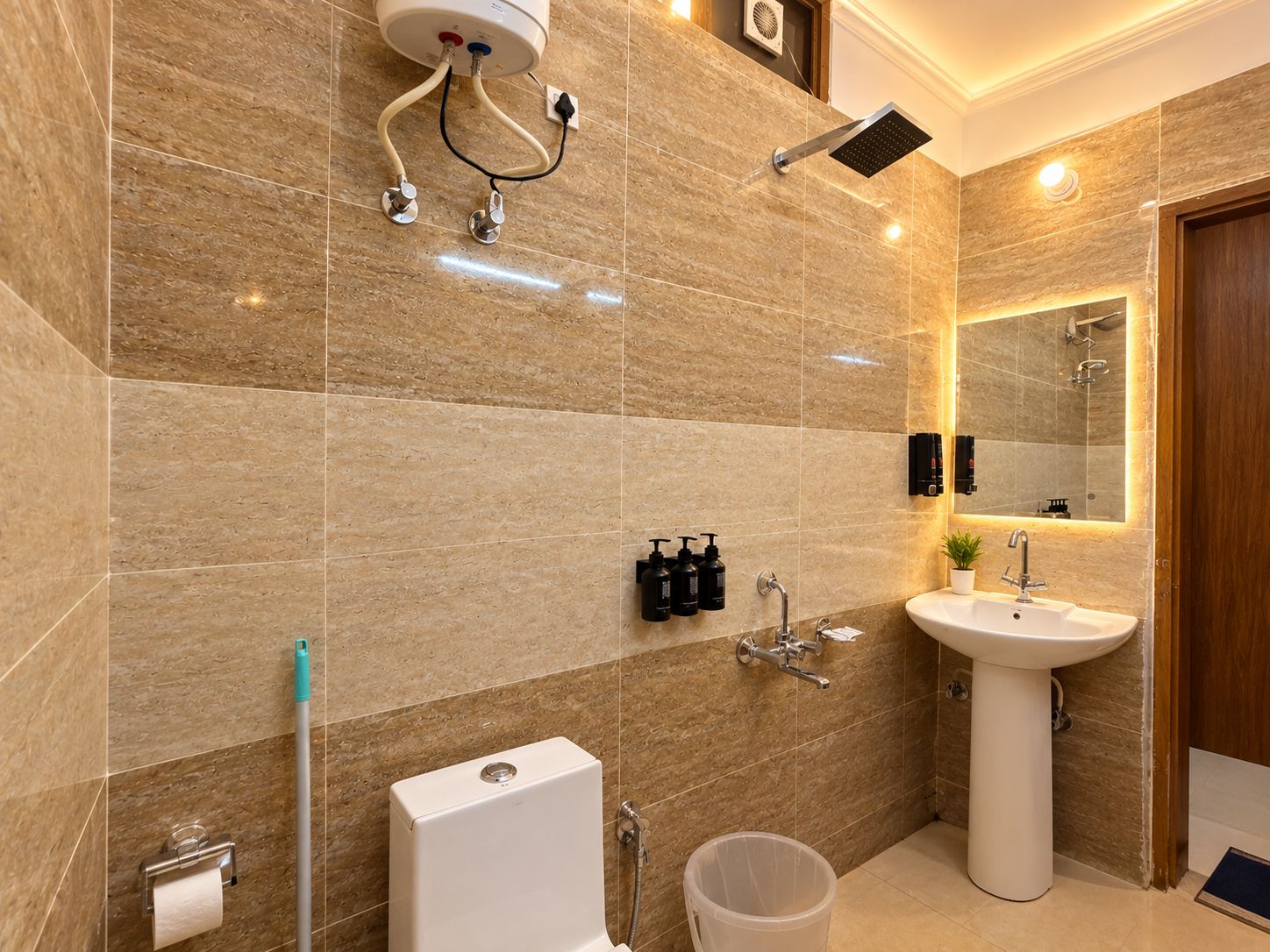 Un baño moderno con piso de mármol, lavamanos pedestal, cabezal de ducha de mano y espejo montado en la pared.