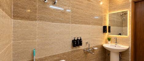 Un baño moderno con piso de mármol, lavamanos pedestal, cabezal de ducha de mano y espejo montado en la pared.
