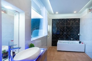 A modern bathroom with a large bathtub, a glass-enclosed shower, and a large mirror.