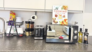 A kitchen counter with a toaster, a coffee machine, spice jars, a bag of chips, and a cookbook titled "Cooking step by step". - Perfect 2 bed Apartment 4 Contractors Sleep Upto 5 (London)