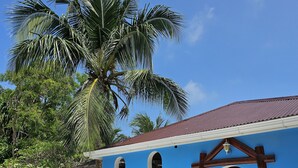 Un coche antiguo blanco aparcado frente a un edificio con fachada azul y un cartel que dice 'Island Luxury Fehendhoo'.