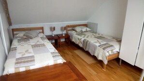 A small, tidy room with two single beds, wooden headboards, a nightstand with a lamp, and a wooden floor. - Maison Bord de mer (Sarzeau)