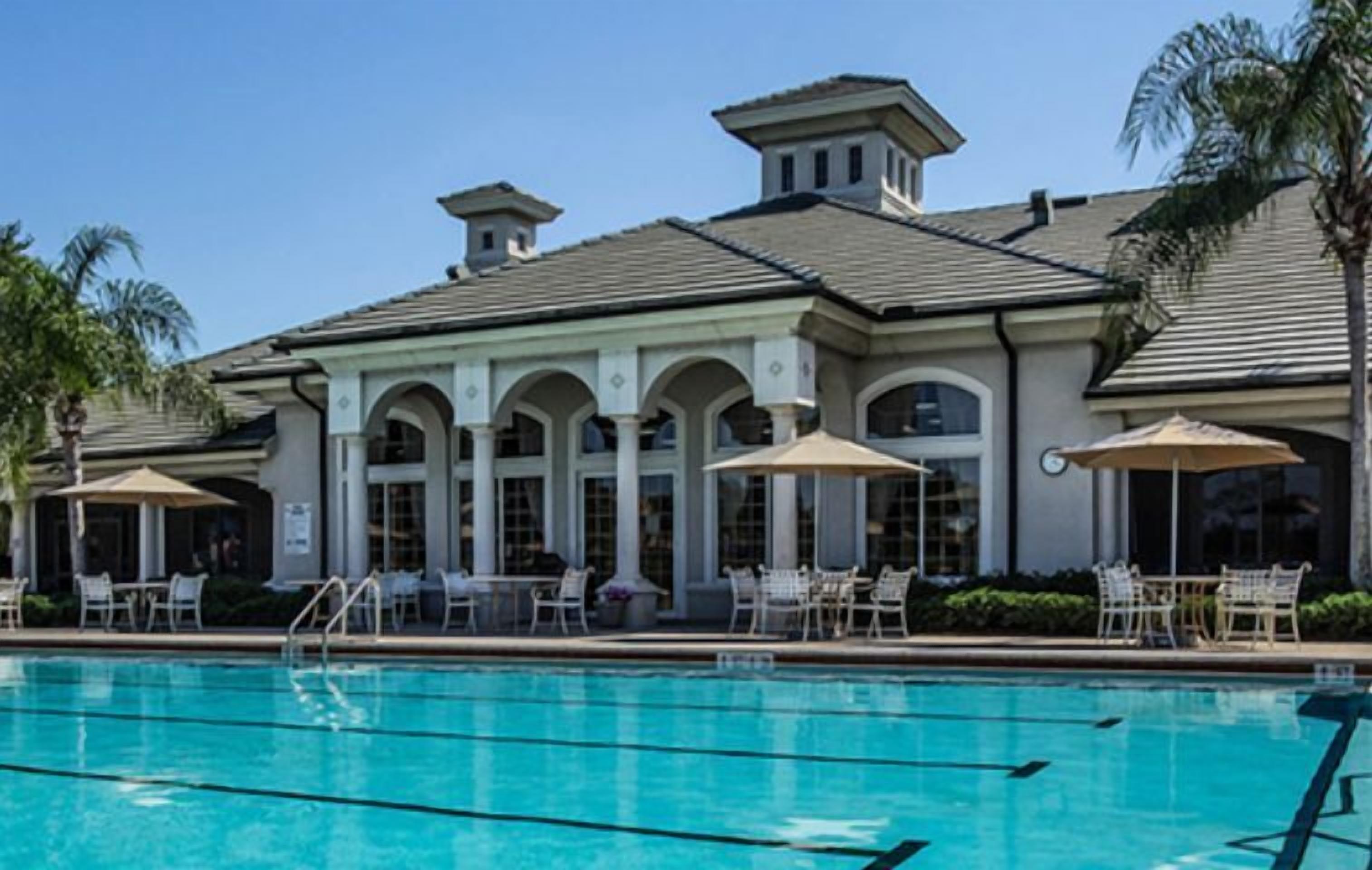 A pool area with a building featuring arched windows and outdoor seating.