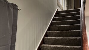 Una escalera con peldaños alfombrados y barandilla de madera.
