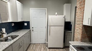 Una cocina compacta con refrigerador, pileta y encimeras de granito.
