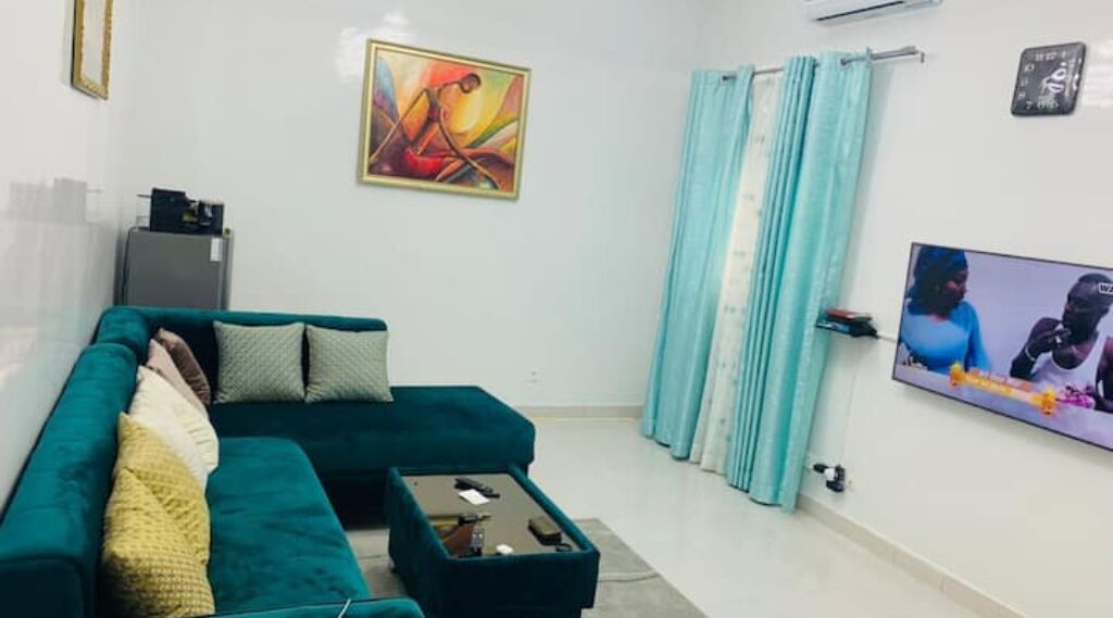 A living room with a teal sofa, a coffee table, a TV, and a painting on the wall.