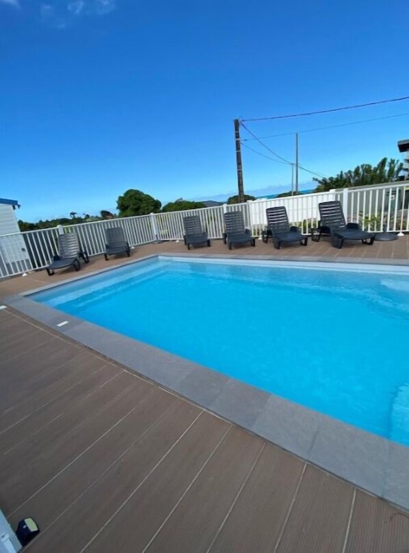 A swimming pool with lounge chairs and a wooden deck.