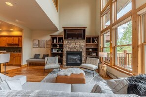A spacious living area with a fireplace, wooden furniture, and large windows. - Stunning Treasury Point condo, 3BD/3BA+Hot Tub! (Mt. Crested Butte)