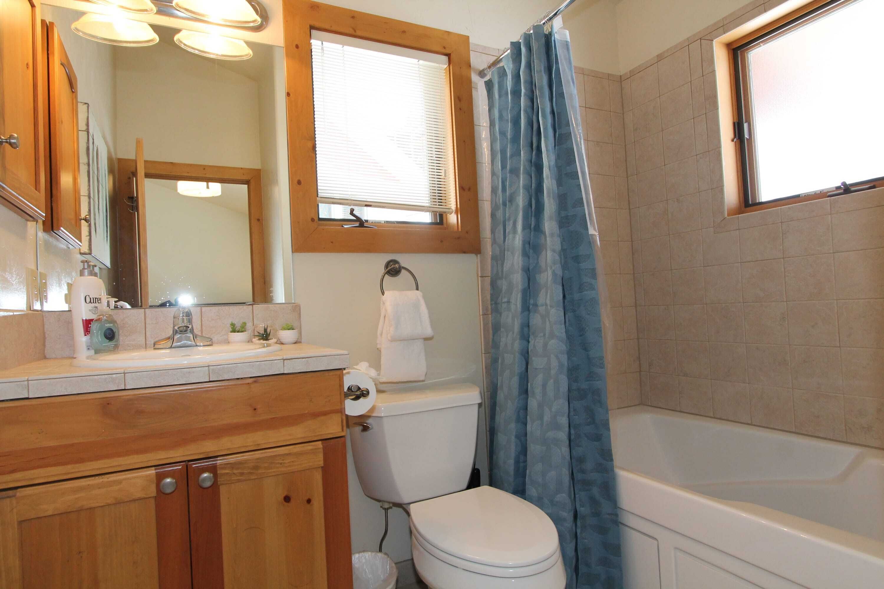 A bathroom with a toilet, sink, mirror, and shower curtain.