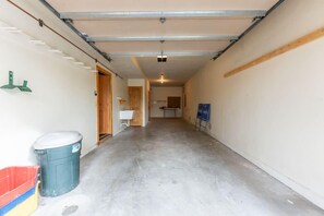 A narrow hallway with a concrete floor, a garage door at the end, and a trash bin on the left. - Stunning Treasury Point condo, 3BD/3BA+Hot Tub! (Mt. Crested Butte)