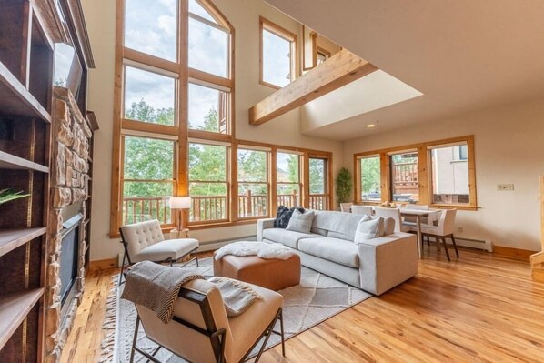 A spacious living room with a large window, a fireplace, and a dining area. - Stunning Treasury Point condo, 3BD/3BA+Hot Tub! (Mt. Crested Butte)