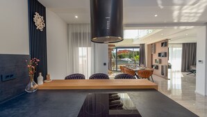 Een moderne keuken met een centraal eiland, een ingebouwde kookplaat en een grote, zwarte afzuigkap.