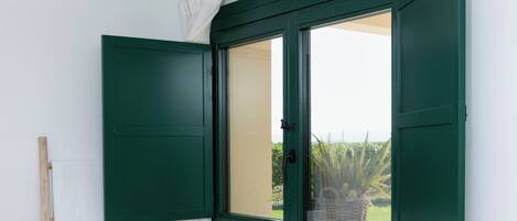 Un baño con una bañera independiente, un ventanal con contraventanas verdes y una escalera de madera.