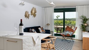 A modern living room with a dining area, a view of a vineyard, and a large window with curtains. - Villas Finca La Emperatriz (Baños de Rioja)