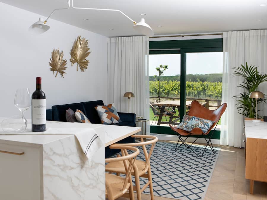 Un salon moderne avec un coin repas, une vue sur un vignoble et une grande fenêtre avec des rideaux.