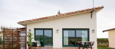 A modern house with a patio, a dining area with outdoor furniture, and a large sliding glass door.