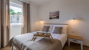 Una cama bien hecha con una bandeja de desayuno, una mesita de noche y un cuadro en la pared.