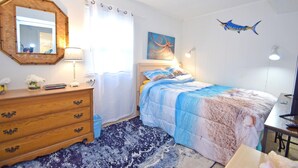 Quarto com cama, cômoda, espelho e obras de arte.