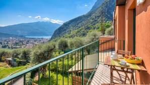 Uma varanda com mesa posta para o café da manhã, com vista para uma paisagem montanhosa e uma cidade abaixo.