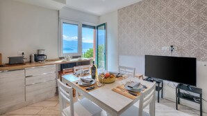 Uma cozinha moderna com área de refeições, janelas amplas e uma televisão de tela plana.