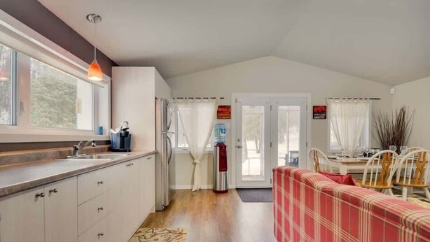 A kitchen with a sink, refrigerator, and a dining area with a table and chairs. - Ô Petit Chalet | Retraite en nature by Alchalet (Saint-Raymond)