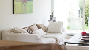 A living room with a white sofa, a coffee table, and a painting on the wall.