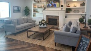 A modern living room with a fireplace, two sofas, a coffee table, and a chandelier. - Boyd Farmhouse Inn (DeWitt)