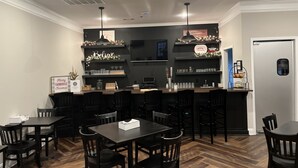 A restaurant with a bar area, wooden flooring, and black chairs and tables. - Boyd Farmhouse Inn (DeWitt)