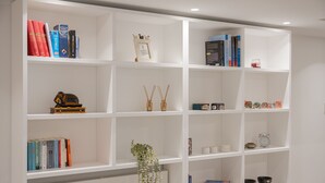 Uma estante branca com livros, objetos decorativos e uma pequena planta.