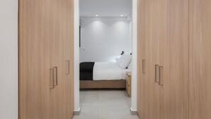 Quarto moderno com armários de madeira, cama com roupa de cama branca e mesa de cabeceira.