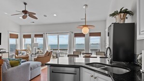 Een moderne keuken met een zwart aanrecht, roestvrijstalen apparatuur en uitzicht op de oceaan.