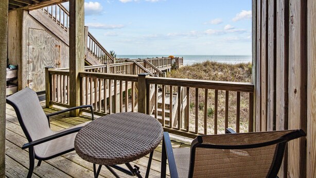 Een houten terras met uitzicht op het strand en de oceaan.