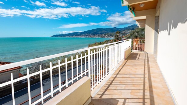 A balcony with a view of the sea and distant mountains.