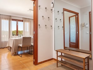 Une chambre d’hôtel comprenant un coin repas, un banc en bois, un miroir et des crochets fixés au mur.