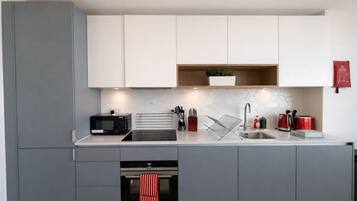 A modern kitchen with grey cabinets, a microwave, a toaster, a sink, and a red-striped towel hanging.