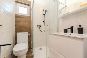 A modern bathroom with a toilet, shower, and sink. - Apartments Plantosar (Vir)