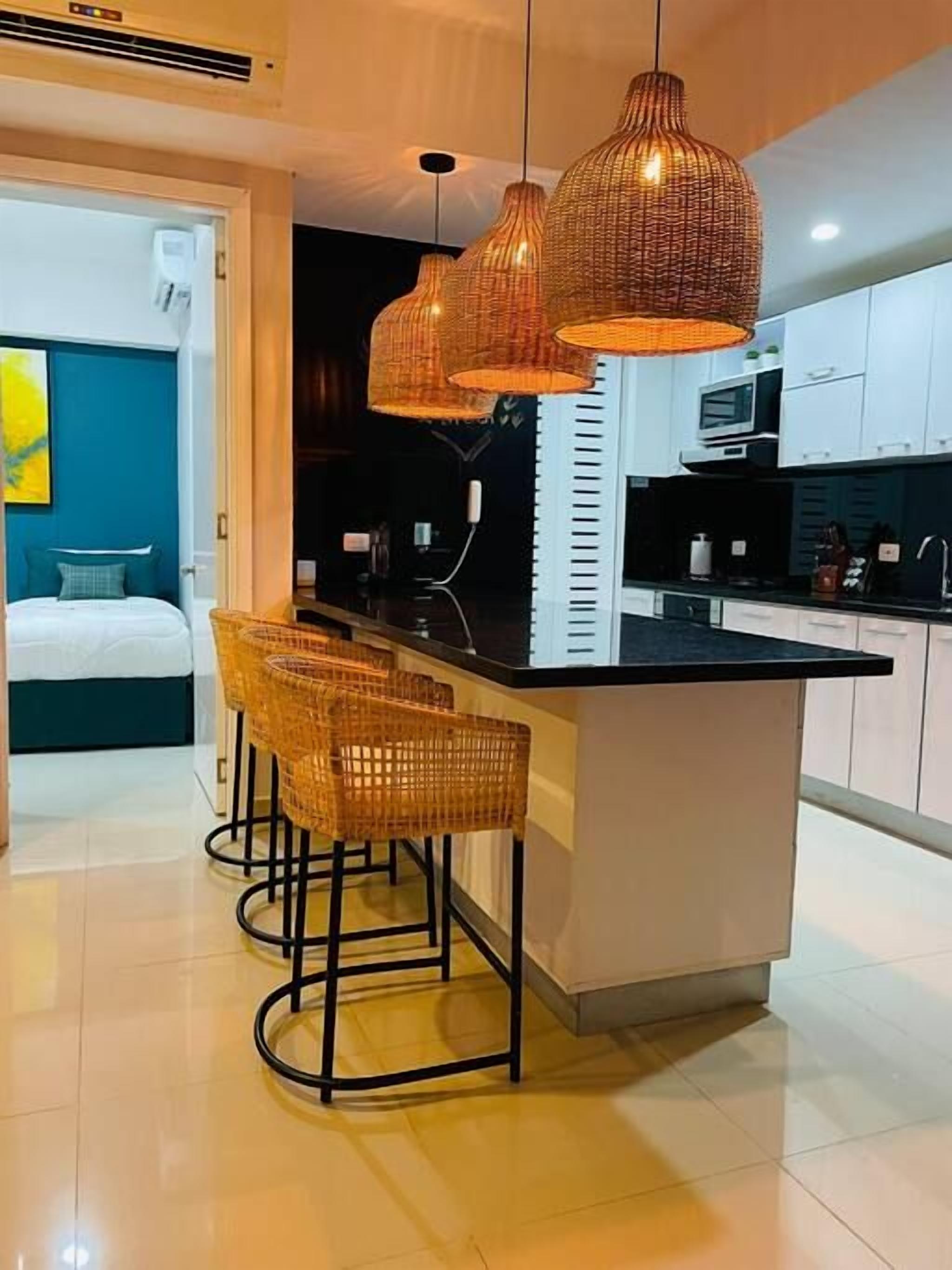 Une cuisine moderne dotée d’un îlot central, de tabourets de bar et de luminaires suspendus.